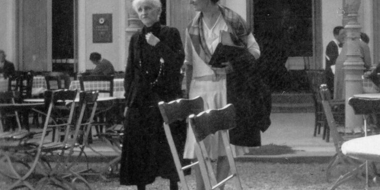 Bertha Pappenheim und Hannah Karminski schlendern durch einen Biergarten und unterhalten sich.