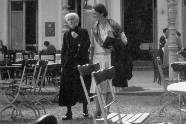Bertha Pappenheim und Hannah Karminski schlendern durch einen Biergarten und unterhalten sich.
