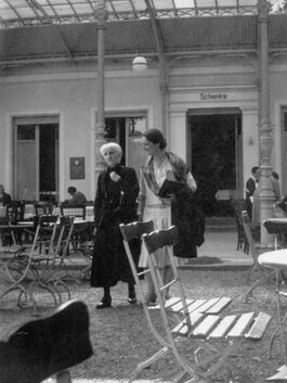 Bertha Pappenheim und Hannah Karminski schlendern durch einen Biergarten und unterhalten sich.