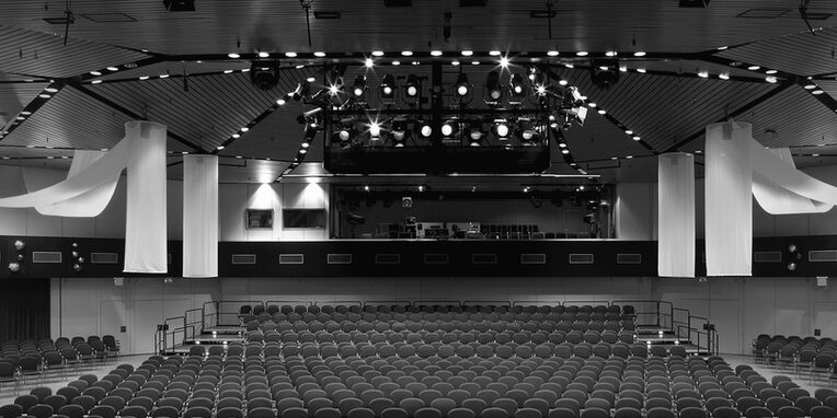 Schwarz-weiß Foto der Hugenottenhalle vom Innenraum mit Bestuhlung