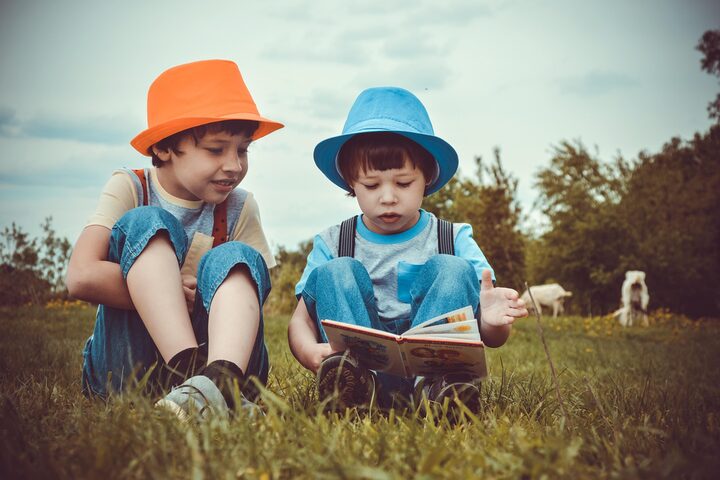 Kinder lesen im Gras sitzend ein Buch