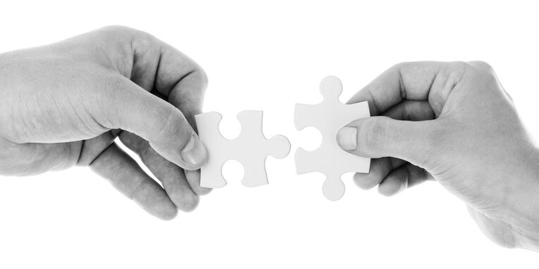 zwei Hände verbinden zwei Puzzleteile miteinander