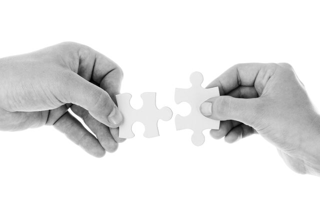 zwei Hände verbinden zwei Puzzleteile miteinander