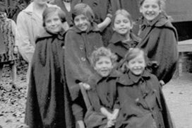Schwarz-weiß-Aufnahme von mehreren Kindern auf einem alten Holzwagen.