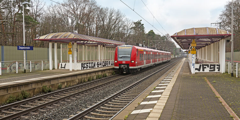 S-Bahnstation in Zeppelinheim mit stehender roter S-Bahn auf der linken Seite