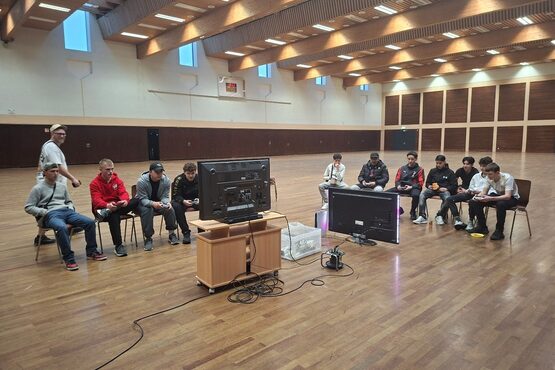 Männer an der Spielekonsole in einer Turnhalle