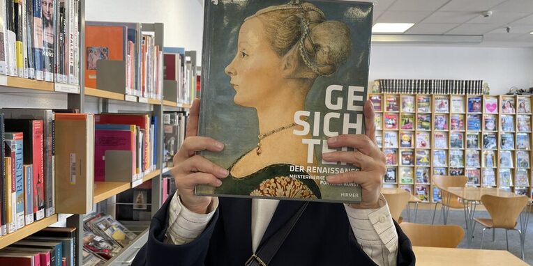 Frau, die sich ein Buch vor das Gesicht hält