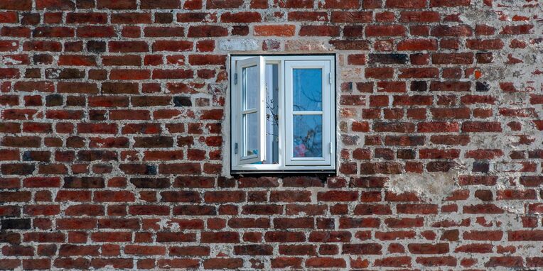 ein geöffnetes Fenster in einem Haus mit Klinkersteinen