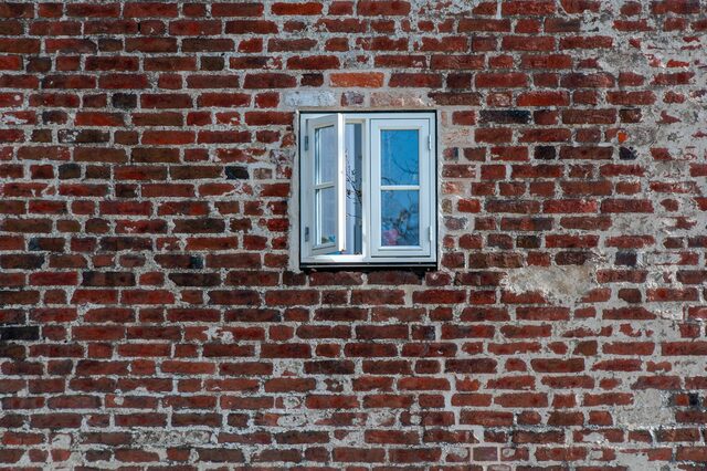 ein geöffnetes Fenster in einem Haus mit Klinkersteinen