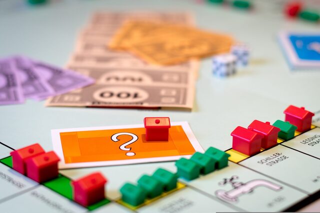 Ein Spielbrett mit grünen und roten kleinen Häusern, Geldscheinen und Karten