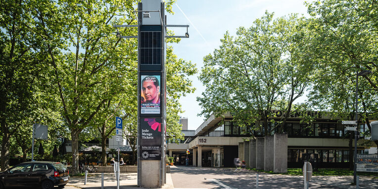 Blick auf die Hugenottenhalle und Stadtbibliothek im Vordergrund die digitale Infosäule