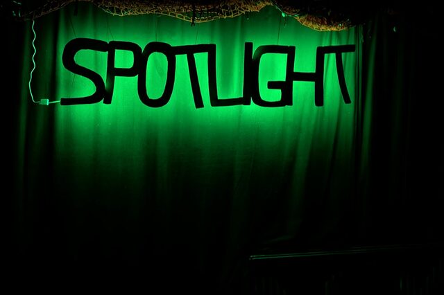 Schwarzer Schriftzug SPOTLIGHT auf grünen leuchtenden Hintergrund