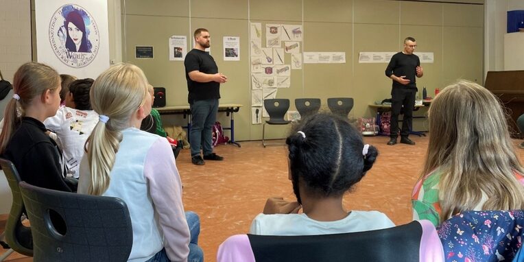 Foto (NWvL): Die 3c der Grundschule Buchenbusch lauscht den Theaterpädagogen Can und Tobias vom Tugce Alybayrak e.V.