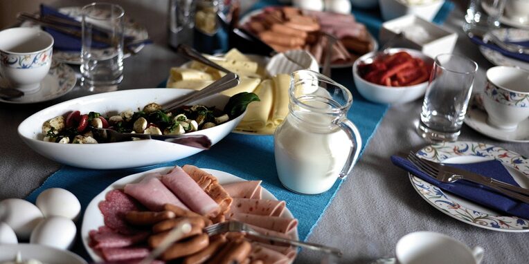 Ein gedeckter Frühstückstisch mit Wurst, Käse, Eier, Kaffeegeschirr