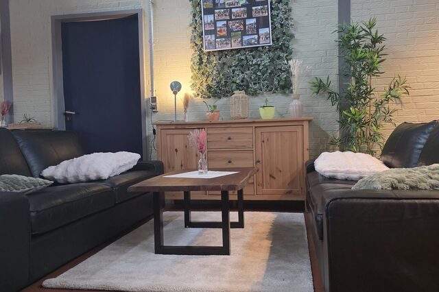 Neu gestaltetes Ambiente des Jugendraums  mit schwarzen Ledersofas, Tisch und einem Sideboard
