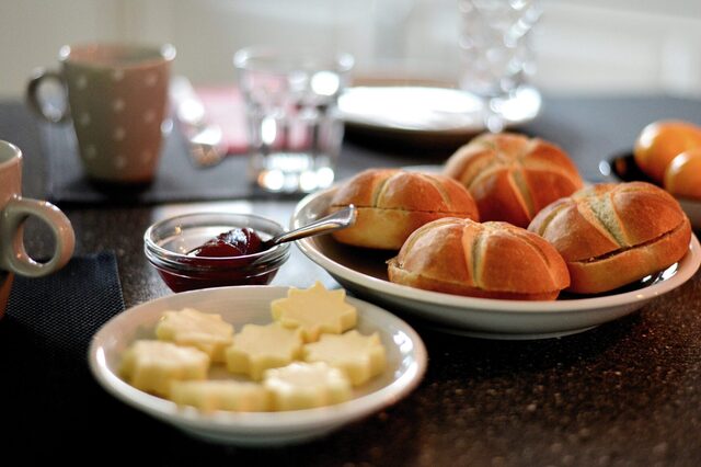Frühstückstisch mit Brötchen, Butter, Marmelade und Eier
