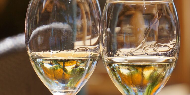 2 Weingläser halb gefüllt mit Wein auf einem Holztisch