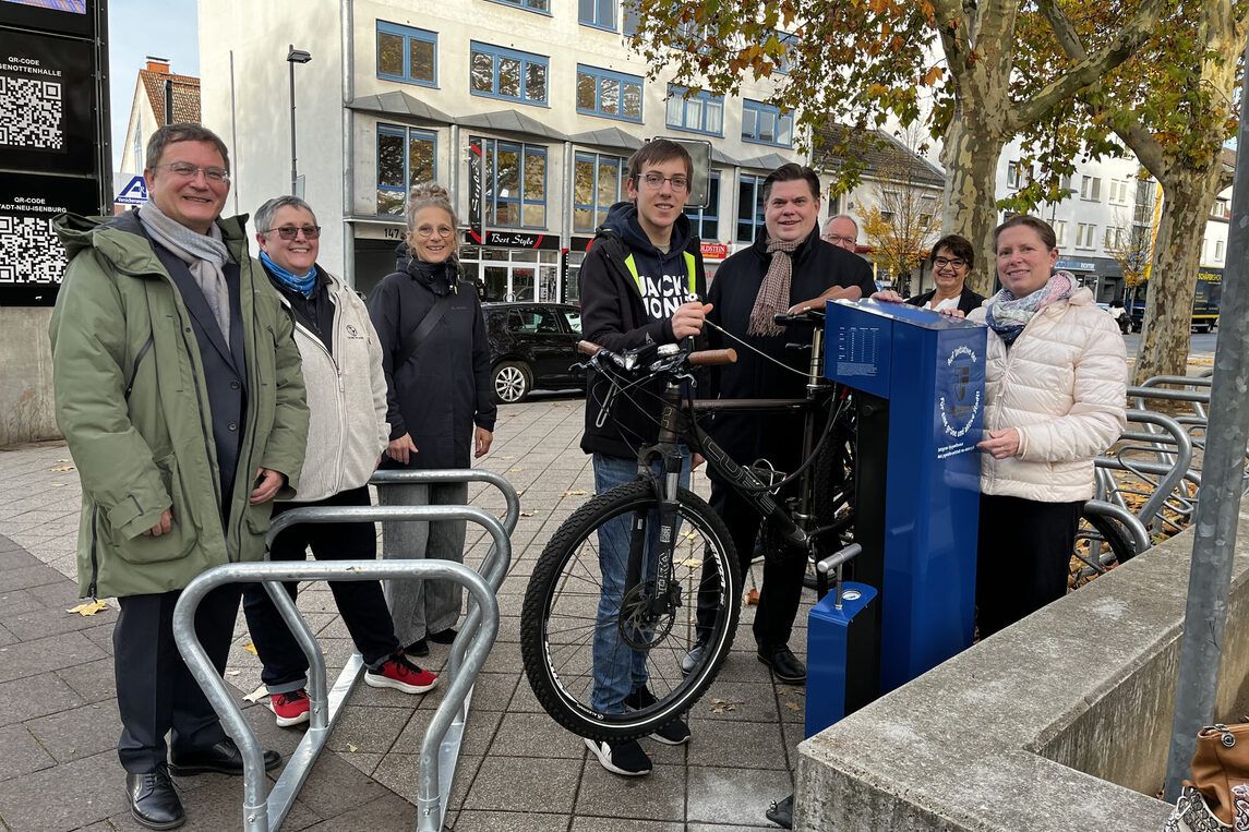 Rad-Reparaturstation und ein Element der mobilen Fahrradständer. Vlnr: Bürgermeister Dirk Gene Hagelstein, Yvonne Lammersdorf, Beauftragte Nahmobilität, Karin Rohde, Fahr-radkoordinatorin, Christian Adam, Jugendforum, Erster Stadtrat Stefan Schmitt, Stadtver-ordnetenvorsteherin Christine Wagner. Im Hintergrund vlnr: David Cappel, Fachbereichs-leitung Stadtbibliothek und Katja Harjes, stellvertretende Fachbereichsleitung Stadtbiblio-thek.