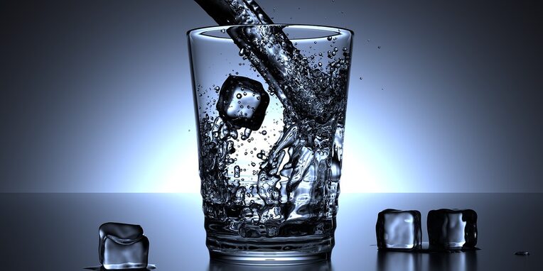 Ein Glas, dass symbolisch mit Wasser und Eiswürfeln gefüllt wird