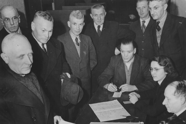 Das Bild zeigt die Stimmabgabe des Bürgermeisters Wilhelm Arnoul bei der Gemeinderatswahl am 27. Januar 1946 im Wahllokal in der Westendhalle. Zu sehen sind daneben v.l.n.r.: Georg Koser, Adolf Bauer, Philipp Wiemer, Adam Ebner, August Geiß (sitzend), Dr. Juliane Girardi-Vogt, Heinrich Zimbrich, Unbekannt, Fotograf: Paul Zehner, Offenbach]. Quelle: Stadtarchiv NI F 2.3 Nr. 49 Bld. 1