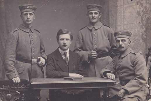 Ludwig Arnoul (links stehend in Uniform hinter seinem älteren Bruder Wilhelm in Zivil, sitzend am Tisch; die beiden anderen Soldaten sind unbekannt)